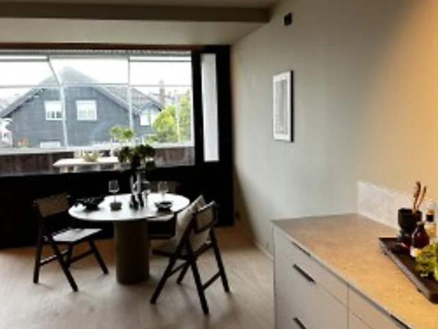 Kjøkken og spiseplass med rundt bord ved vinduet