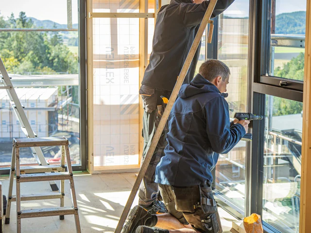 Håndverkere monterer vinduer i bygg under rehabilitering